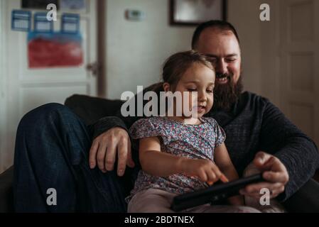 Primo piano di papà e bambina che giocano sul tablet durante l'isolamento Foto Stock