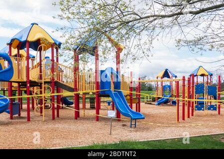 Worcester, Pennsylvania - 8 aprile 2020: I parchi giochi sono chiusi fino a nuovo avviso di fronte al colorato parco giochi rosso, giallo e blu Foto Stock