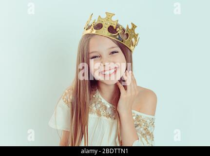 Mini Miss giovane ragazza felice con una bella sorridente ridendo indossando una corona e un abito bianco su vacanza guardando voi fotocamera isolato sfondo verde Foto Stock