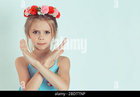 Bambino isolato ragazza che mostra le braccia incrociate stop segno mani gesto isolato bianco luce verde sfondo Foto Stock