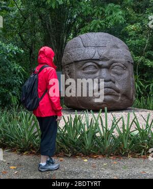 Donna che guarda la scultura di testa di Giant Olmec nel museo la Venta Olmec a Villahermosa, Tabasco, Messico Foto Stock