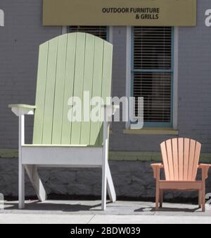 Un gigante di dimensioni sedia Adirondack si trova al di fuori di un negozio con una minore, facciata normale sedia accanto ad esso Foto Stock