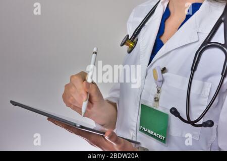 Farmacista che lavora con la compressa. Stetoscopio sulla spalla, badge visibile Foto Stock