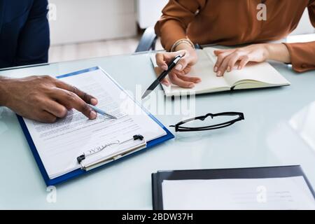 Due imprenditori mano analizzando il documento sulla scrivania in vetro Foto Stock