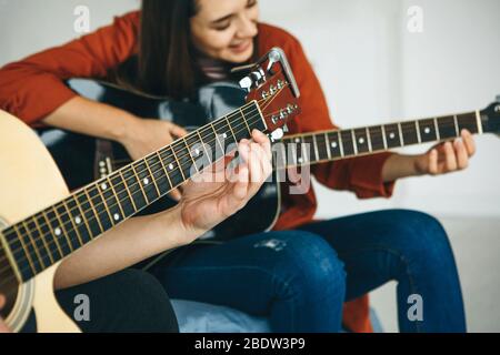 Imparare a suonare la chitarra. L'insegnante spiega allo studente le basi per suonare la chitarra. Lezioni individuali di scuola domestica o extracurricolare. Foto Stock