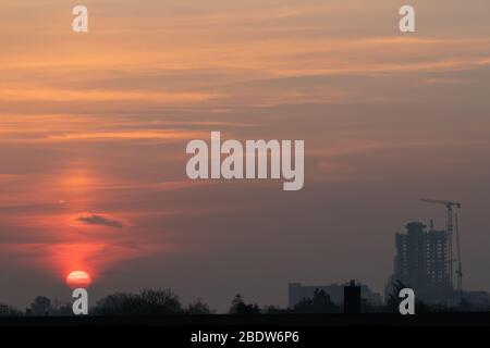 Un sole ardente illumina uno skyline roseo sopra Londra Ovest Foto Stock