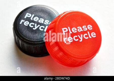 Tappo nero e rosso del flacone con messaggio di riciclo su sfondo bianco. Concetto di inquinamento plastico. Foto Stock