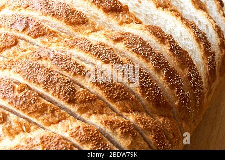 Fette di pane. Closeup estremo di pane bianco appena sfornato a fette di paese con una crosta croccante per l'uso come sfondo da forno. Foto Stock