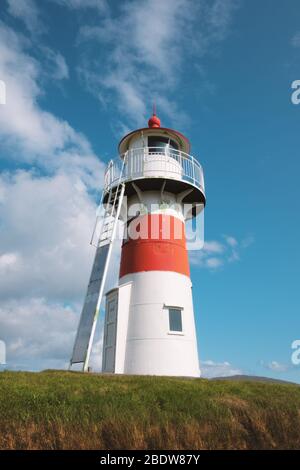 Vecchio faro fuori città di Torshavn contro cielo blu chiaro, Isole Faroe, Danimarca Foto Stock