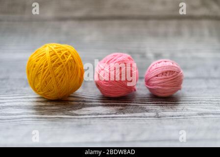 Tre palle di lana colred che si stendono su sfondo grigio di legno. Foto Stock