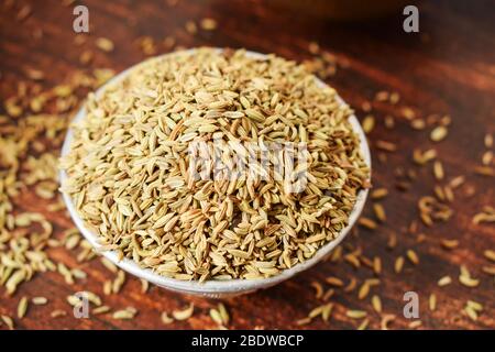 Semi di finocchio secchi in una ciotola d'argento su tavolo vecchio di legno. Stile rustico Foto Stock