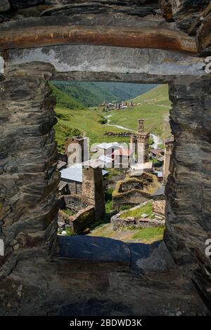 Vista del villaggio di Ushguli attraverso una finestra della torre. Ushguli è una comunità di villaggi situata alla testa della gola di Enguri nell'alta Svaneti, Georgia (CA Foto Stock