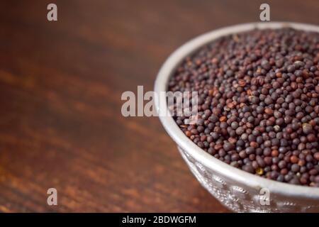 Semi di senape in una ciotola d'argento su tavolo vecchio di legno. Stile rustico Foto Stock