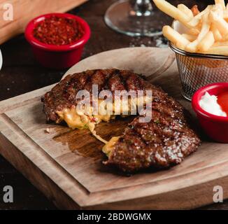 bistecca di carne fritta con formaggio su tavola di legno Foto Stock