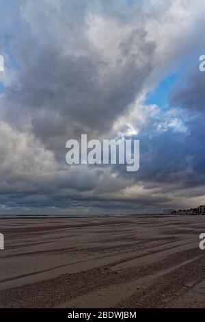 Dunkerque Beach e Sea Front con persone che camminano lungo di esso sotto un cielo drammatico in una ventosa mattina di novembre. Foto Stock