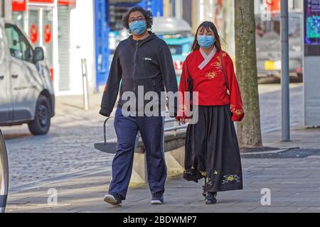 Nella foto: Una giovane coppia che indossa maschere facciali nel centro della città di Swansea, Galles, Regno Unito. Mercoledì 25 Marzo 2020 Re: Covid-19 Coronavirus pandemic, UK. Foto Stock