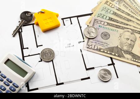 Alcune banconote in dollari statunitensi, oltre a una calcolatrice e a una chiave di casa in cima ai piani di costruzione. Foto Stock