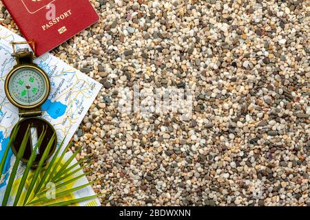 Bussola, passaporto, mappa e ramo felce sullo sfondo della spiaggia di sabbia. Foto Stock