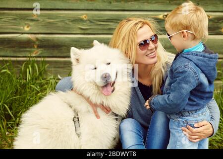 ritratto esterno madre, figlio e cane. bambino e mamma che cammina samoyed laika. Foto Stock