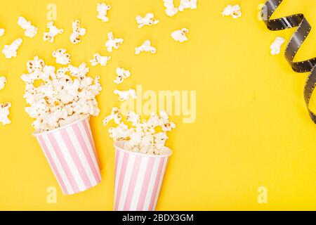 Secchio popcorn e striscia di pellicola su sfondo giallo. Film o sfondo TV. Vista superiore spazio di copia Foto Stock