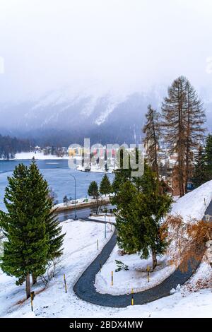 Saint Moritz, Svizzera - 20 dicembre 2019 - una piccola strada tortuosa conduce al lago surgelato Saint Moritz a Saint Moritz, Svizzera, con una nevicatura fredda Foto Stock