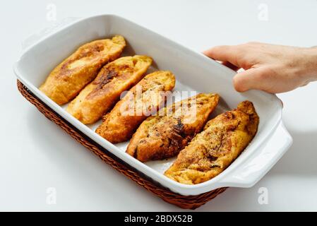 Mano maschile con un vassoio con torrijas, un tipico dolce spagnolo fritto toast di pane affettato imbevuto di uova e latte, su sfondo bianco. Tradizionale Foto Stock