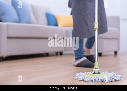 Pavimenti per mop. Giovane donna lavaggio in legno piano terra a casa con un mop, pulizia attrezzature, concetto di antibatterico, prevenzione virus, primo piano. Foto Stock