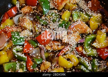 Mescolare appena preparato friggere con pollo e verdure, inclusi cipolle, capsicum rosso, giallo e verde in un wok Foto Stock