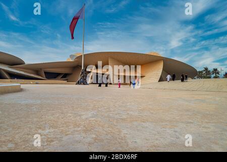Museo Nazionale del Qatar (rosa del deserto) In Qatar Doha vista luce esterna con bandiera Qatar e. nuvole nel cielo Foto Stock