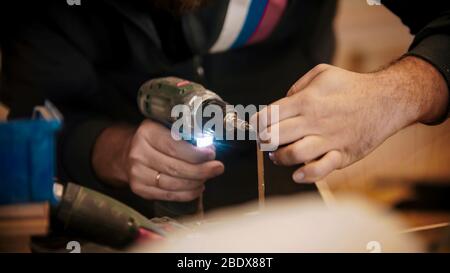 Industria carpenteria - lavoratore che fora i fori in pezzo di compensato. Scatto intermedio Foto Stock