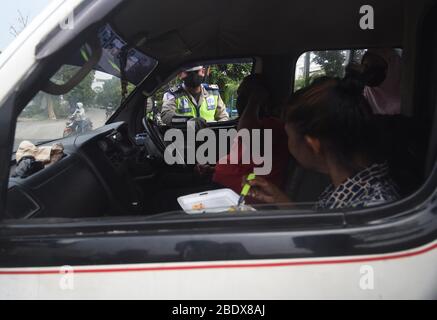 Giacarta, Indonesia. 10 aprile 2020. Un poliziotto indonesiano ispeziona un veicolo presso un punto di controllo come l'attuazione delle restrizioni sociali su larga scala nella periferia di Giacarta, Indonesia, 10 aprile 2020. Venerdì il governo indonesiano ha detto che il numero di casi confermati di COVID-19 nel paese è salito a 3,512 e il numero dei decessi è salito a 306. Il presidente indonesiano Joko Widodo ha dichiarato un'emergenza sanitaria pubblica per la pandemia di coronavirus ed ha emesso un regolamento governativo sulle restrizioni sociali su larga scala. Credit: Zulkarnain/Xinhua/Alamy Live News Foto Stock