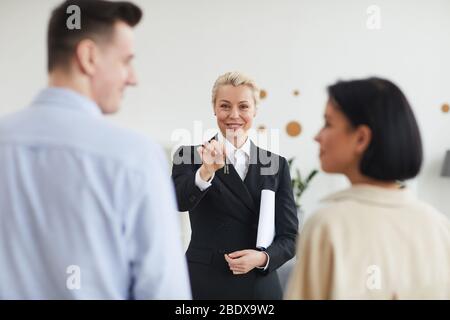 Il realtor riuscito in vestito nero che dà le chiavi alla coppia giovane che comprano una nuova casa Foto Stock