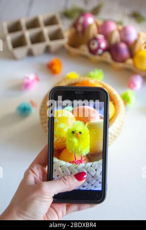Donna che prende la foto sul suo smartphone di uova di Pasqua e decorazioni. Foto Stock