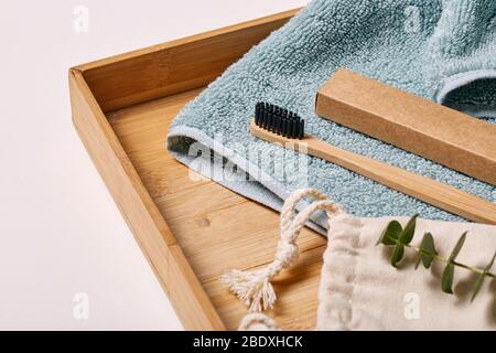 Mattina Grooming. Spazzolino da denti in bambù su asciugamano su vassoio di legno Foto Stock