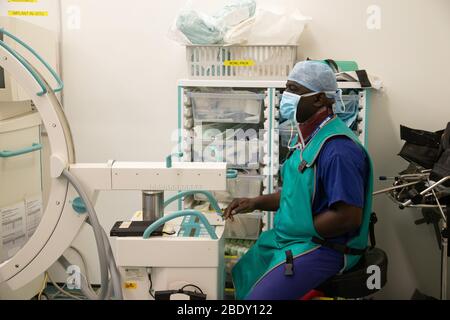 Un anestesista controlla l'apparecchiatura e monitora i progressi dei pazienti in un ospedale durante un intervento. Foto Stock