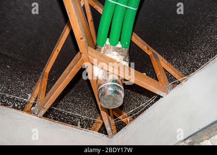 Ventilazione a recupero energetico domestico, sistema visibile di tubi flessibili verdi e diffusore di alimentazione dell'aria, distribuito sulle capriate del tetto. Foto Stock