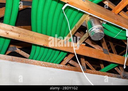 Ventilazione a recupero energetico domestico, sistema visibile di tubi flessibili verdi e diffusore di alimentazione dell'aria, distribuito sulle capriate del tetto. Foto Stock