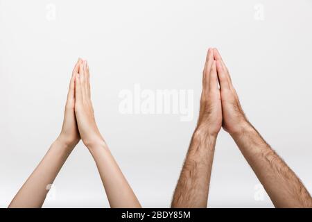 Immagine di primo piano delle mani sollevate di un uomo e di una donna isolata su sfondo bianco muro mostrando prego gesto di preghiera. Foto Stock