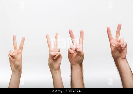 Immagine di primo piano delle mani sollevate di un uomo e di una donna isolate su sfondo bianco della parete che mostra un gesto di pace. Foto Stock