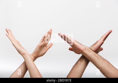 Foto di primo piano delle mani di un uomo e di una donna isolate su sfondo bianco della parete che mostra il gesto di arresto. Foto Stock