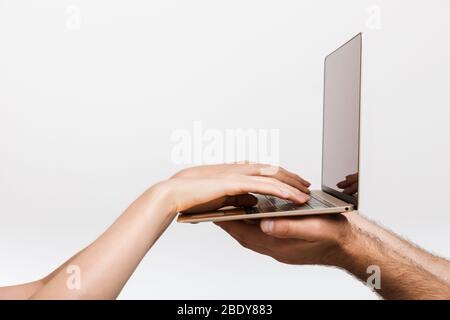 Immagine di primo piano delle mani di un uomo e di una donna isolata su sfondo bianco parete che tiene la digitazione computer portatile. Foto Stock