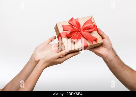 Foto di primo piano delle mani di un uomo e di una donna isolate su sfondo bianco parete che tiene una scatola regalo sorpresa. Foto Stock