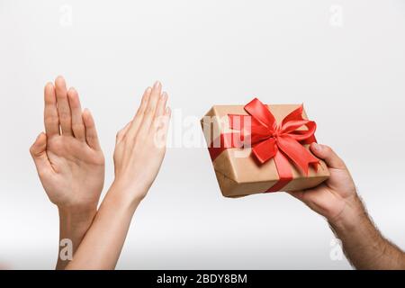 Immagine closeup delle mani della donna che mostra stop gesto mentre il suo uomo isolato su sfondo bianco parete che tiene presente confezione regalo. Foto Stock