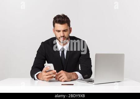L'attraente imprenditore caucasico preoccupato e stanco parlare sul telefono cellulare seduto alla scrivania dell'ufficio che lavora in stress ha funzionato eccessivamente e frustrato. Foto Stock
