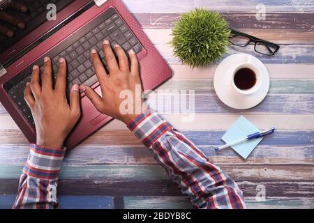 vista ad alta angolazione del giovane che digita sul laptop. Foto Stock
