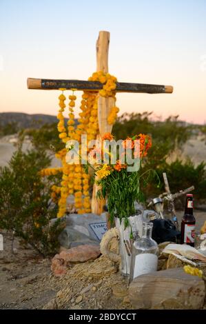 Una croce di legno decorata con marigolds nel Cimitero di Terlingua nel Texas occidentale, dove le tombe sono segnate da abbellimenti fatti a mano. Foto Stock