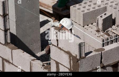 Lavoratore su cantiere costruzione costruzione costruzione Breeze Block muro. Foto Stock