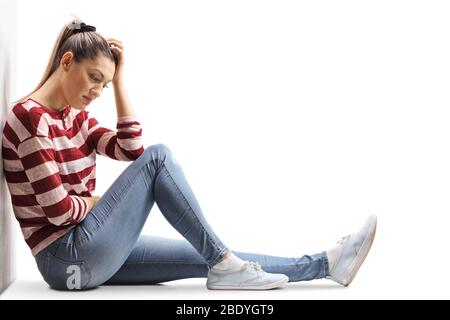 Triste giovane donna seduta sul pavimento con testa in giù isolata su sfondo bianco Foto Stock