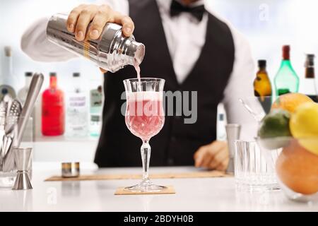 Barman che versa un cocktail in un bicchiere in un bar Foto Stock