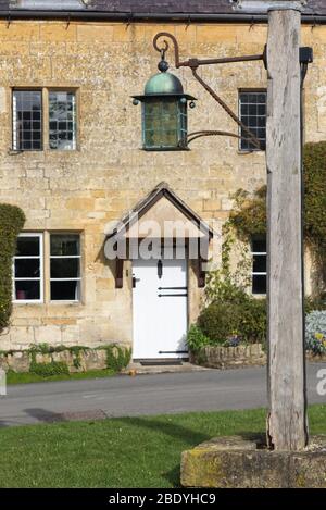 Lampada d'epoca su un palo di legno incorporato in una pietra nel villaggio di Stanton Foto Stock